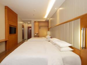 a bedroom with two large white beds and a tv at GreenTree Alliance Jiangsu Huai'an Suning Plaza in Huai'an