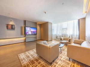 a living room with couches and a flat screen tv at GreenTree Eastern Hotel Lanzhou Zhongchuan Airport Eastern Airlines Center in Lanzhou