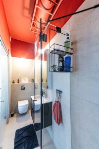 a bathroom with a toilet and a sink with an orange ceiling at My TLV City suite in Tel Aviv +4 photos