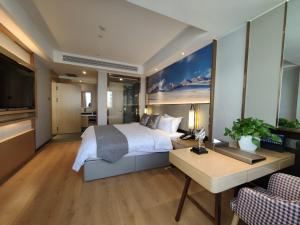 ein Hotelzimmer mit einem Bett, einem Schreibtisch und einem TV in der Unterkunft GreenTree Eastern Hotel Xinjiang Urumqi Renmin Road in Ürümqi