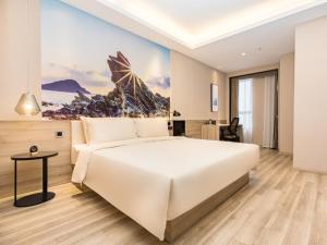 a bedroom with a large white bed and a table at GreenTree Eastern Hotel Shenzhen Pinghu Hua'nan City Hehua Subway Station in Longgang