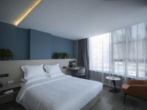 a bedroom with a large white bed and a window at Geli Hotel Suqian Shuyang Yingbin Avenue in Shuyang
