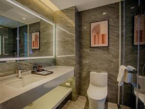 a bathroom with a sink and a toilet and a mirror at VX Hotel Nanning Chaoyang Plaza Nanhu Park in Nanning