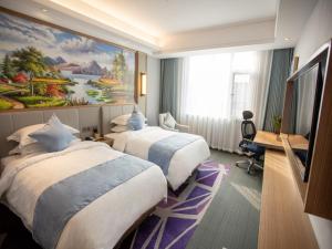 BinzhouにあるGreenTree Eastern Hotel Binzhou Zhonghai International Convention and Exhibition Centerのベッド2台が備わる客室で、壁には絵画が飾られています。