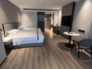 a bedroom with a bed and a desk and a table at GreenTree Eastern Hotel Fuyang Jieshou Railway Station East Xinyang Road in Xiaosongzhuang