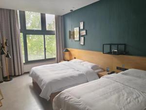 Habitación de hotel con 2 camas y ventana en GreenTree Inn Lanzhou Zhongchuan Airport, en Hejialiang