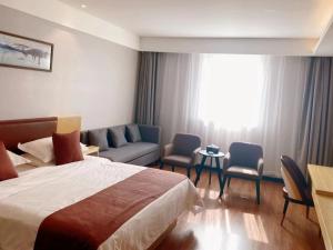 TaozhuangにあるGeli Hotel Zaozhuang High-Speed Railway Stationのベッド、椅子、ソファが備わるホテルルームです。