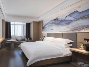 a bedroom with a large bed with a painting on the wall at GreenTree Eastern Hotel Chuzhou Suchu Industrial Park in Chuzhou
