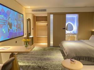 a hotel room with a bed and a flat screen tv at Geli Hotel Bengbu Wanda Plaza Nanxiang City in Bengbu