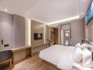 una camera da letto con un grande letto bianco e una televisione di Gya Hotel Suzhou Hanshan Temple Binhe Road a Suzhou