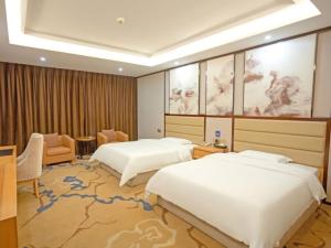 YichunにあるVX Hotel Yichun Yuanzhou Government High-Speed Railwayのベッド2台とソファが備わるホテルルームです。