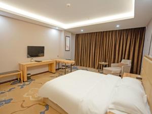 YichunにあるVX Hotel Yichun Yuanzhou Government High-Speed Railwayのベッド、デスク、テレビが備わるホテルルームです。