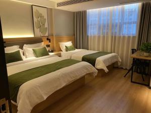 a hotel room with two beds and a window at GreenTree Inn Express Hotel Suzhou Zhangjianggang Free Trade Zone Central Plaza in Zhangjiagang
