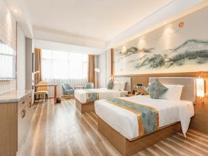 um quarto de hotel com duas camas e uma secretária em GreenTree Eastern Hotel Huai'an Suning Plaza West Huaihai Road em Huai'an