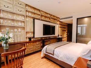 GEM Hotel Bozhou College في Bozhou: غرفة نوم بسرير وتلفزيون بشاشة مسطحة