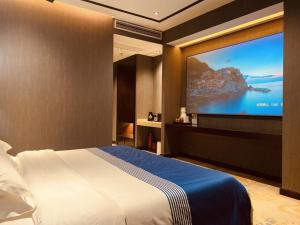 a bedroom with a bed and a flat screen tv at Geli Hotel Bengbu Wanda Plaza Nanxiang City in Bengbu