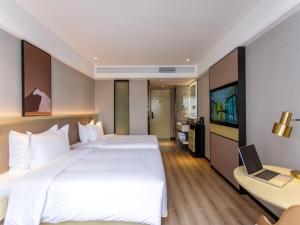 una habitación de hotel con 2 camas y un ordenador portátil en un escritorio en VX Hotel Nanning Chaoyang Plaza Nanhu Park, en Nanning