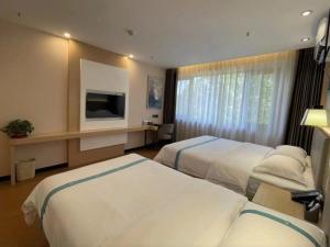 a hotel room with two beds and a television at VX Hotel Tianjin West Yongyang Road Florentia Town in Wuqing