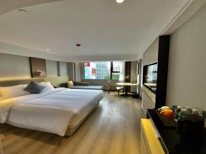 a bedroom with a large white bed and a desk at VX Hotel Nanning Chaoyang Plaza Nanhu Park in Nanning