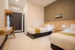 a hotel room with two beds and a desk at El Ora Hotel & Eatery Labuan Bajo in Labuan Bajo