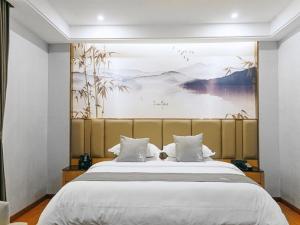 ZhenningにあるGreenTree Eastern Hotel Anshun Anshun Zhenning Huangguoshuのベッドルーム1室(壁に絵画が描かれた大型ベッド1台付)