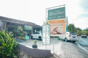 een bord voor een winkel waar auto's voor geparkeerd staan bij El Ora Hotel & Eatery Labuan Bajo in Labuan Bajo