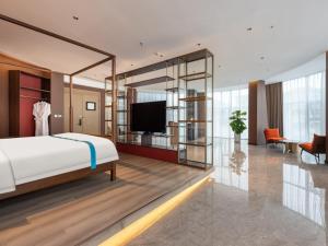 a bedroom with a bed and a tv in a room at GreenTree Eastern Hotel Fuyang Jieshou Railway Station East Xinyang Road in Xiaosongzhuang