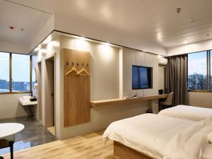 太倉市にあるGreenTree Inn Express Hotel Suzhou Taicang West Nanjing Roadのベッドルーム(ベッド1台、テレビ、デスク付)