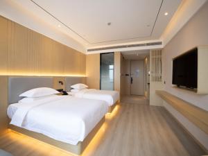 a hotel room with two beds and a flat screen tv at Deep Sleep Hotel Hangzhou Dajiang East Haide Xingang Center in Hangzhou