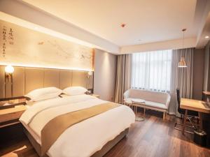 una camera d'albergo con un grande letto e una scrivania di GreenTree Eastern Hotel Anhui Xuancheng Guangde Old Cross Street a Guangde