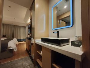 a bathroom with a sink and a bed and a mirror at GreenTree Eastern Hotel Xinjiang Urumqi Renmin Road in Ürümqi