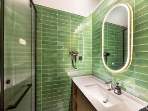een groene betegelde badkamer met een wastafel en een spiegel bij GreenTree Inn Express Hotel Changzhou Wujin Economic Development Zone Qishuyan Yaoguan in Changzhou