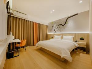 Un dormitorio con una gran cama blanca y un escritorio. en Vatica Hotel Shuyang Central Mall Nanjing Road, en Shuyang