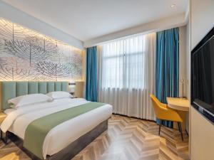 een hotelkamer met een groot bed en een bureau bij GreenTree Inn Express Hotel Changzhou Wujin Economic Development Zone Qishuyan Yaoguan in Changzhou