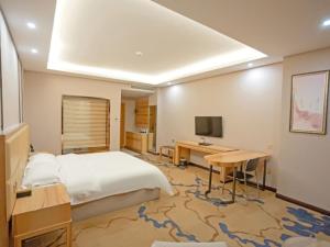 Schlafzimmer mit einem Bett, einem Schreibtisch und einem TV in der Unterkunft VX Hotel Yichun Yuanzhou Government High-Speed Railway in Yichun