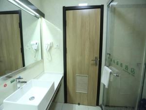 uma casa de banho com um lavatório e um chuveiro com um espelho. em GreenTree Inn Anqing East Yingbin Road High-Speed Railway Station em Anqing