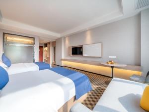 a hotel room with two beds and a tv at GreenTree Inn Yulin Hongjin Markey Yide in Yulin