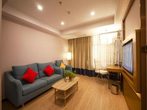 uma sala de estar com um sofá azul e almofadas vermelhas em GreenTree Eastern Hotel Hebi Jun County Passenger Station em Xun