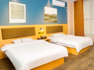 two beds in a hotel room with two beds at Geli Hotel Hefei Modian University Mengxi Town in Hefei