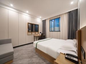 太倉市にあるGreenTree Inn Express Hotel Suzhou Taicang West Nanjing Roadのベッドとテレビが備わるホテルルームです。