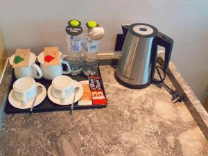 ein Tablett mit Tassen und eine Kaffeemaschine auf der Theke in der Unterkunft Geli Hotel Zaozhuang High-Speed Railway Station in Taozhuang