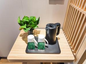 a table with a tea kettle and a plant on it at VX Hotel Tianjin West Yongyang Road Florentia Town in Wuqing