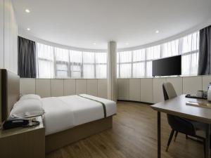 a hotel room with a bed and a desk and a tv at GreenTree Inn Express Hotel Suzhou Taicang West Nanjing Road in Taicang