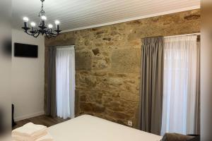 een slaapkamer met een stenen muur, een bed en een kroonluchter bij Casa Rural Depende in Vilagarcia de Arousa