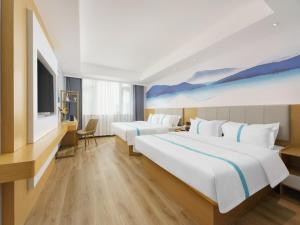 een hotelkamer met 2 bedden en een flatscreen-tv bij VX Hotel Dalian Zhoushuizi Airport in Dalian