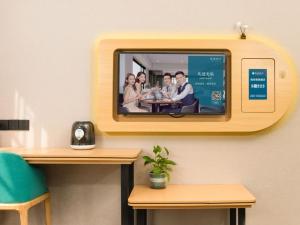 a tv hanging on a wall with a group of people at Geli Hotel Hefei Modian University Mengxi Town in Hefei