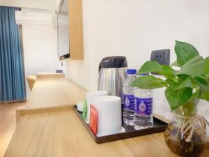 a tray with a coffee maker and a plant on a table at GreenTree Inn Guangdong Zhanjiang Donghai Island in Zhanjiang