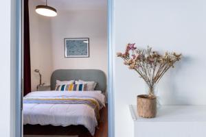 a bedroom with a bed and a vase of flowers at My TLV City suite in Tel Aviv