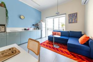 a living room with a blue couch and a kitchen at My TLV City suite in Tel Aviv