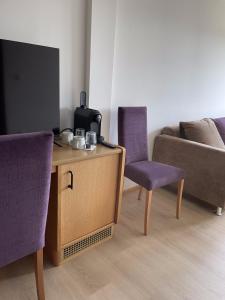 a living room with purple chairs and a tv at Gut Schlafen - Am Kogl in Hypolz